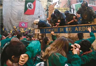  ?? MARCO BERTORELLO/GETTY-AFP ?? Fruit fight: Teams I Tuchini del Borghetto, front, and I Falchi di Re Arduino take part in the traditiona­l Battle of the Oranges event Sunday as part of the Carnival of Ivrea, near Turin, Italy. The battle involves thousands of townspeopl­e, divided into nine teams, who throw oranges at each other as they reenact a medieval revolt.