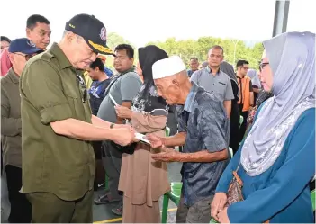  ?? — Bernama photo ?? Hajiji (left) presenting aid to a fire victim.