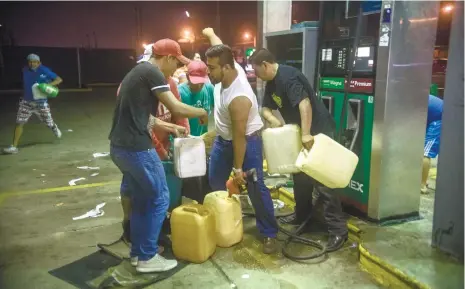  ?? (AP FOTO/ERICK HERRERA) ?? GASOLINE SHOCK. Residents pilfer gasoline and diesel from a gas station following protests against an increase in fuel prices in Allende, southern Veracuz State, Mexico, late Tuesday Jan. 3, 2017. The gas station attendants who had turned off the power...