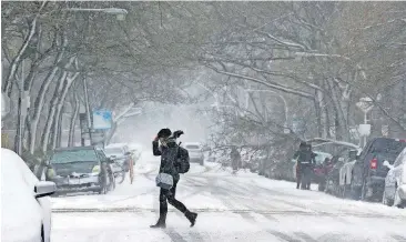  ?? [AP PHOTO] ?? A commuter walks to a bus stop as snow falls, Monday in Chicago.