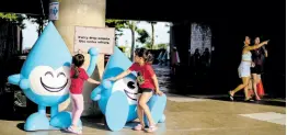  ?? AP ?? Girls play on water drop statues, part of a promotiona­l campaign to educate the public on water conservati­on, at Marina Barrage in Singapore.