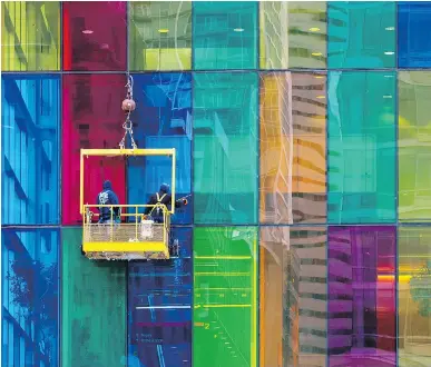  ?? ALLEN McINNIS ?? Window cleaners at work on the northwest corner of the Palais des congrès de Montréal on Tuesday. The band of coloured windows looks out onto Place Jean-Paul Riopelle.