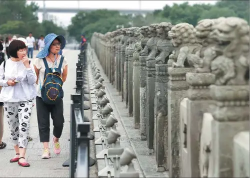  ?? WANG ZHUANGFEI / CHINA DAILY ?? Tourists examine the stone lions at the Lugou Bridge in south Beijing.