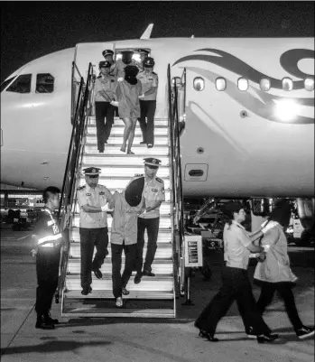  ?? HAO FEI / FOR CHINA DAILY ?? Seventeen suspects allegedly involved in telecommun­ication fraud are escorted from a chartered plane that arrived in Chengdu, Sichuan province, on Thursday from Cambodia.