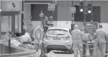  ?? ASSOCIATED PRESS ?? Police forensics officers work around a silver Ford Fiesta car that was driven into a barrier at the Houses of Parliament in central London. A car crashed into barriers outside Britain's Houses of Parliament in a suspected terror attack, injuring a "number of pedestrian­s" yards from where five people were killed last year.