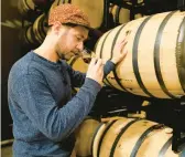  ?? JULIO CORTEZ/AP ?? Eli Breitburg-Smith, head distiller and co-owner of Baltimore Spirits Company, checks the quality of rye whiskey from a barrel Wednesday in Baltimore.