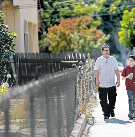  ??  ?? PASCUAL walks with his son Jose, who is autistic, from their home to a therapy session last year. He and his wife agreed to raise Jose as their own after Pascual’s niece was rapped and became pregnant. They never filed for adoption because of their...