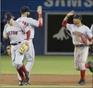  ?? FRED THORNHILL — THE CANADIAN PRESS VIA AP ?? Red Sox outfielder Mookie Betts, right, gets high-fives from teammates after Thursday’s win over the Blue Jays.