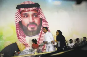  ?? Amr Nabil / Associated Press 2019 ?? A Saudi family passes a poster of Crown Prince Mohammed bin Salman in Jiddah last year. Salman is trying to boost the kingdom’s internatio­nal image.