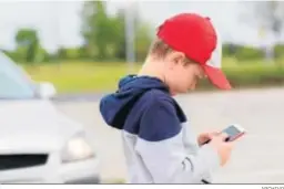  ?? ARCHIVO ?? Un niño maneja un móvil en la calle.