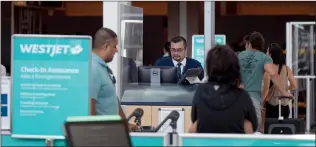  ?? CANADIAN PRESS PHOTO ?? A WestJet employee assists passengers at the domestic check-in area at Vancouver Internatio­nal Airport, Friday in Richmond, B.C.