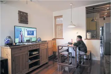  ??  ?? Sha Jie, 10, a primary school student, attends an online Chinese class as he sits at home in Shanghai.