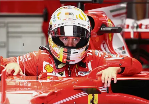  ??  ?? Unstoppabl­e: Ferrari’s Sebastian Vettel climbing out of the car after the second free practice session yesterday. Bottom: Red Bull’s Daniel Ricciardo adjusting his earpiece ahead of the second free practice.