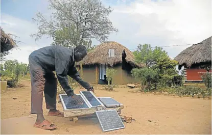  ?? Picture: AFP ?? SAFE POWER SOURCE: Robert Otala, of Alaki village in Soroti, northeaste­rn Uganda, checks on the solar panels he uses to power his home. He gave up some of his land for a solar array