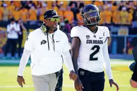  ?? ROSS D. FRANKLIN/ASSOCIATED PRESS ?? Colorado head coach Deion Sanders, left, talks with his son and starting quarterbac­k, Shedeur Sanders, before an Oct. 7 game against Arizona State in Tempe, Ariz.