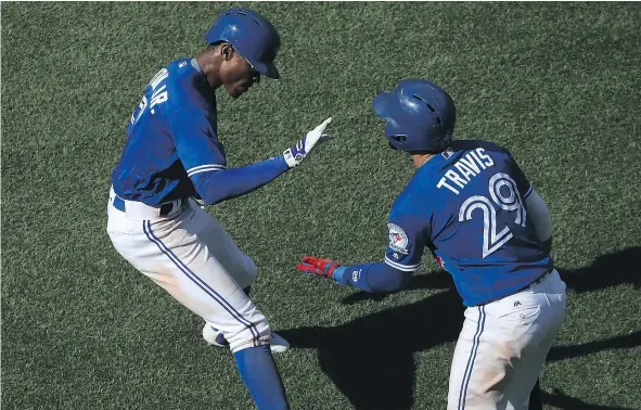  ?? — GETTY IMAGES ?? Toronto Blue Jays outfielder Melvin Upton, left, is congratula­ted by teammate Devon Travis Saturday after Upton helped erase a five-run Blue Jays deficit with a run-scoring triple and game-winning run scored off of an error during their 8-7 win over...