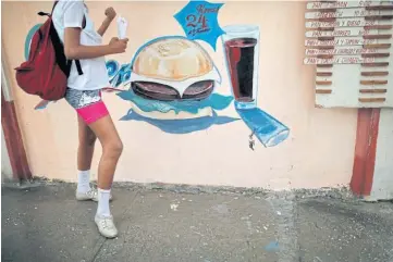  ??  ?? AMERICAN INFLUENCE: A girl stands by a fast food restaurant in the city of Guantanamo.