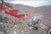  ?? AFP ?? An excavator digs in the debris of demolished houses at the Larung Gar Buddhist Institute in China's Sichuan province. Thousands of monks, nuns and laypersons have been expelled from the area, with authoritie­s warning that the area has become...