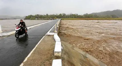  ?? —GRIG C. MONTEGRAND­E ?? SWOLLEN RIVER Amotorcycl­ist drives over Pinaripad Bridge in Aglipay town, Quirino province. Rivers in the region were swollen by rains brought by Typhoon “Rosita.”