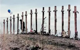  ?? ERIC GAY
THE ASSOCIATED PRESS FILE PHOTO ?? A woman stands among crosses posted on a hill above Columbine High School in Littleton, Colo., in remembranc­e of the people who died during a school shooting on April 20, 1999.