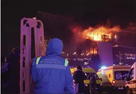  ?? VITALY SMOLNIKOV — THE ASSOCIATED PRESS ?? A medic stands near ambulances parked outside the burning Crocus City Hall in Moscow on Friday. Several gunmen burst into the hall and fired automatic weapons at the crowd.