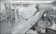  ?? Arkansas Democrat-Gazette/STEPHEN B. THORNTON ?? Curtis Davis stretches for a row of submerged sandbags as he guides his boat to his flooded home in Toad Suck on Dec. 30, 2015. A prison work crew had put a 4-foot wall of sandbags around the home the day before, but water from the Arkansas River kept...