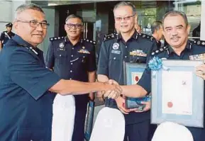  ?? PIC BY MOHD YUSNI ARIFFIN ?? Inspector-General of Police Tan Sri Mohamad Fuzi Harun (left) shaking hands with Seberang Perai Utara district police chief Assistant Commission­er Norzaini Mohd Nor at the police contingent­s’ and districts’ Op Selamat excellence award ceremony in Bukit Aman, Kuala Lumpur yesterday.