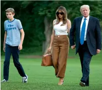  ?? AP ?? Donald Trump, Melania Trump and their son Barron Trump walk from Marine One across the South Lawn to the White House in Washington. After nearly five months of living apart, Melania, announced that she and the couple’s young son have finally moved into...