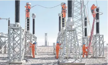  ??  ?? Local workers clean insulators at the Cerro Dominador solar plant’s booster substation. The substation raises the voltage to the 220 kv needed to connect to the grid.