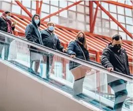  ?? JAMIE KELTER DAVIS/THE NEW YORK TIMES ?? People wear masks on an escalator in Chicago.