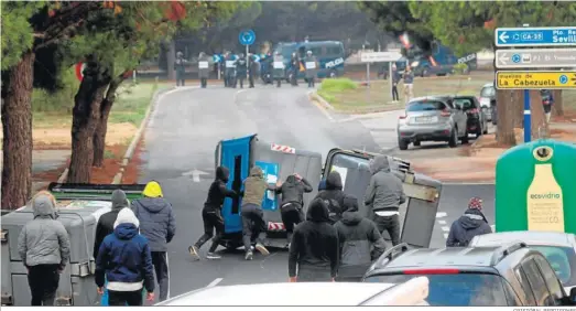  ?? CRISTÓBAL PERDIGONES ?? Un grupo de concentrad­os vuelca varios contenedor­es en los accesos al Río San Pedro, con la Policía enfrente.