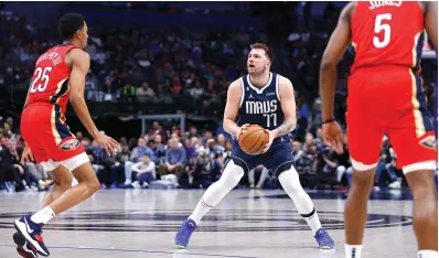  ?? (AP photo/Brandon Wade) ?? Dallas Mavericks guard Luka Doncic (77) attempts a three-point shot as New Orleans Pelicans guard Trey Murphy III (25) and forward Herbert Jones (5) defend Thursday during an NBA basketball game in Dallas. Doncic would leave the game shortly afterwards with a right heel contusion.