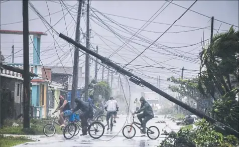  ?? Adalberto Roque/AFP/Getty Images ?? Residents return home after the passage of Hurricane Irma on Saturday in Caibarien, Cuba. Irma's blast through the Cuban coastline weakened the storm to a Category Three, but it is still packing 125 mile-an-hour winds and was expected to regain power before hitting the Florida Keys early Sunday, U.S. forecaster­s said.