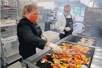  ?? SUSAN STOCKER/SOUTH FLORIDA SUN SENTINEL PHOTOS ?? Chrissy Benoit, manager and chef of the Feeding South Florida Community Kitchen, and Steven Jones grill vegetables and chicken Tuesday in Boynton Beach. The new kitchen is currently preparing meals for seniors and student programs.