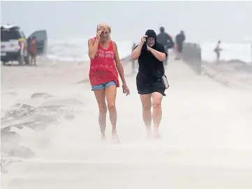  ??  ?? DANGEROUS: People shield their faces from wind and sand in Corpus Christi, Texas.