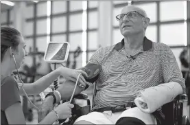  ?? STEVEN SENNE/AP PHOTO ?? William Lytton, of Scarsdale, N.Y., has his vital signs checked by physical therapist Caitlin Geary, left, at Spaulding Rehabilita­tion Hospital in Boston on Tuesday while recovering from a shark attack.