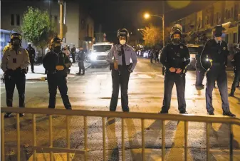  ?? Gabriella Audi / AFP / Getty Images ?? Philadelph­ia police line up to protect the 18th precinct after the city imposed a 9 p. m. curfew after two nights of protests and unrest after the fatal shooting of Walter Wallace Jr.