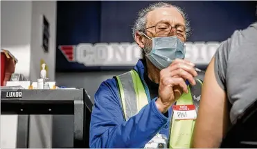  ??  ?? Premier Health Registered Nurse Phil Frederick administer­s a COVID-19 vaccine at the University of Dayton Arena. More than 2.8 million Ohioans have received at least one dose of a vaccine.