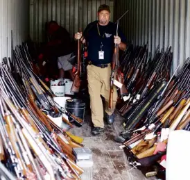  ?? REUTERS ?? A CHESTERFIE­LD County Sheriff’s deputy sorts through thousands of guns found in the home of Brent Nicholson in South Carolina. The question of how one man amassed such a stockpile of guns arises in the wake of a series of mass shootings in the United...