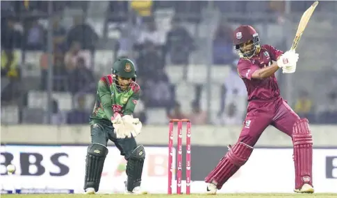  ?? (AFP) ?? West Indies’ Shai Hope (right) plays a shot as Bangladesh’s Mushfiqur Rahim looks on during the second ODI in Dhaka yesterday.