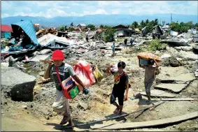  ?? AP/RIFKI ?? People carry items they saved from the rubble Monday after a major earthquake and tsunami Friday in Palu, Central Sulawesi, Indonesia.