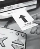  ?? JOHN J. KIM/CHICAGO TRIBUNE ?? Teresa Harvey demonstrat­es how a card is inserted on a new touch-screen voting machine in Chicago on Feb. 21.