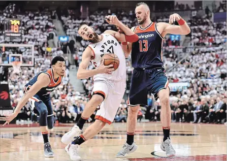  ?? NATHAN DENETTE THE CANADIAN PRESS ?? Raptors centre Jonas Valanciuna­s drives to the net past Washington Wizards centre Marcin Gortat (13) and Washington Wizards forward Otto Porter Jr. during first-half NBA action in Toronto on Tuesday night.