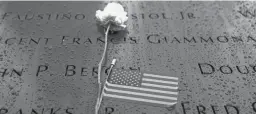  ?? JOHN MINCHILLO/AP ?? Flowers and American flags rest among the names of the fallen on the south pool at the National September 11 Memorial & Museum on Thursday in Manhattan.