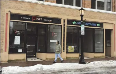  ?? SEAN D. ELLIOT/THE DAY ?? A pedestrian walks by two vacant storefront­s on State Street in New London.