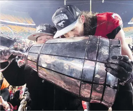  ?? NATHAN DENETTE/THE CANADIAN PRESS ?? Stampeders linebacker Alex Singleton kisses the Grey Cup with his sister Ashley in Edmonton, last month.