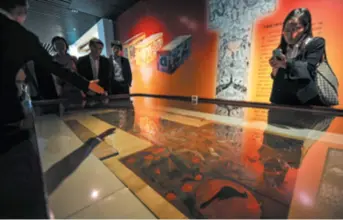  ??  ?? Inside a museum in Changsha, Hunan Province in central China, visitors admire a silk painting unearthed from a Warring State Period tomb, on March 28, 2014