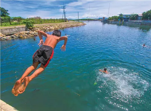  ?? ALDO NELBERT BANAYNAL ?? A boy dives into the water channel along South Road Properties in Barangay Mambaling, Cebu City.
