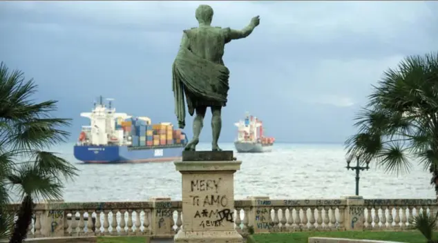 ?? © belgaimage ?? Een standbeeld van Julius Caesar kijkt toe hoe containers­chepen voor anker gaan bij de haven van Napels.