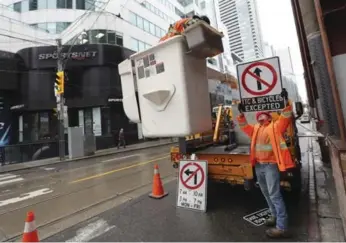  ?? RICHARD LAUTENS/TORONTO STAR ?? A crew from Guild Electric sets up the new traffic signs on King St. at Peter St./Blue Jays Way.